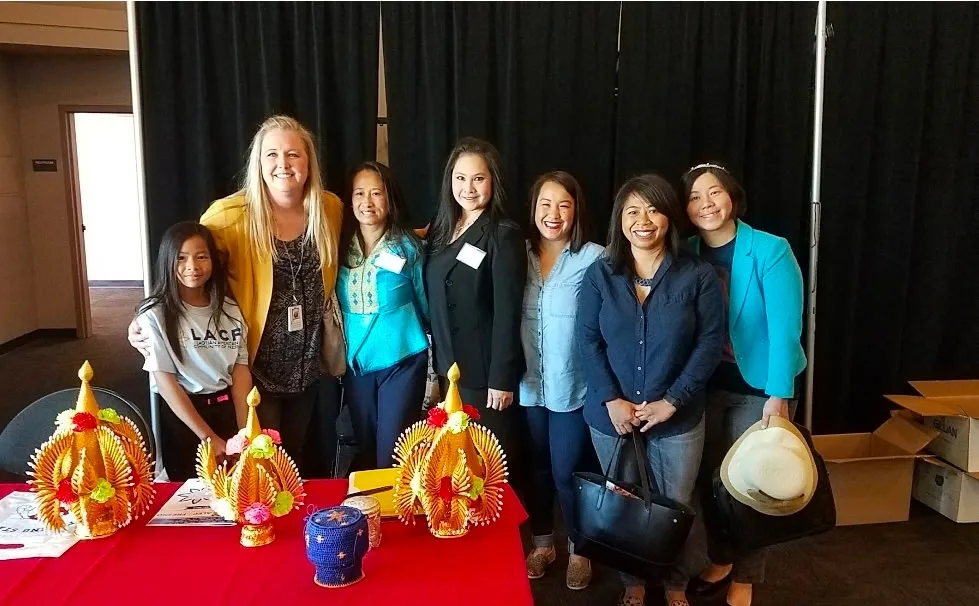 Seven women and a girl standing behind a table of handmade traditional decorations